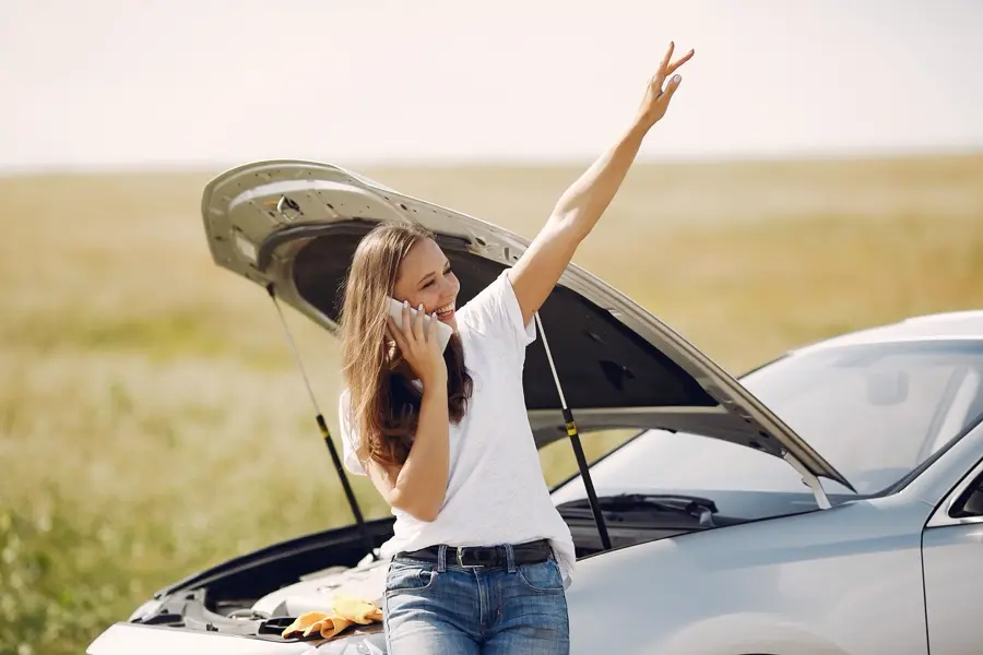 A driver on the phone beside a car with its hood raised (representative photo)