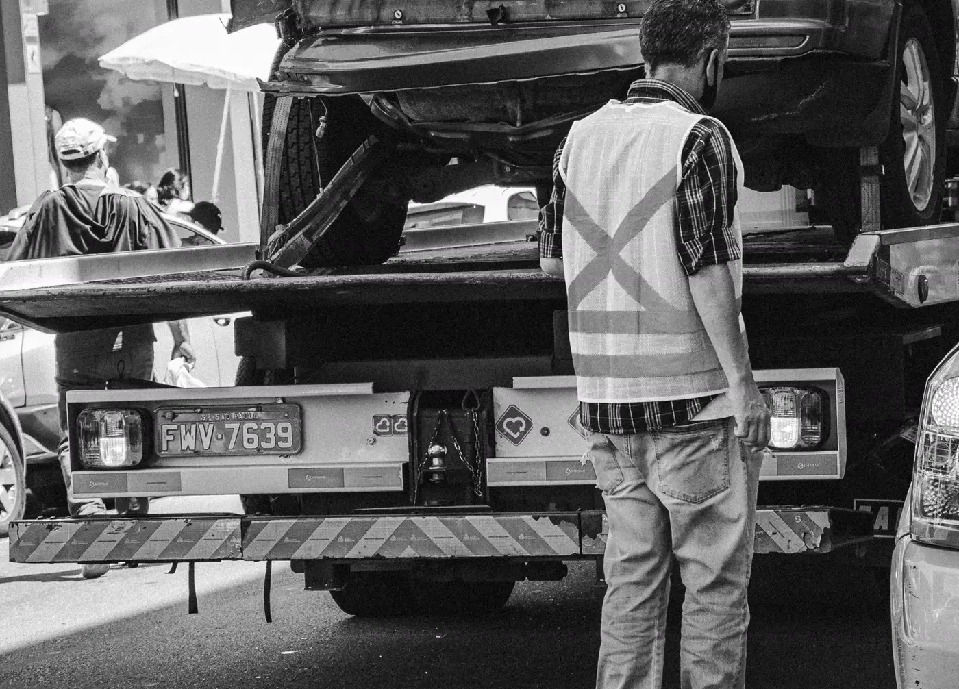 A car loaded on the deck of a tow truck, operator standing at the back (representative photo)