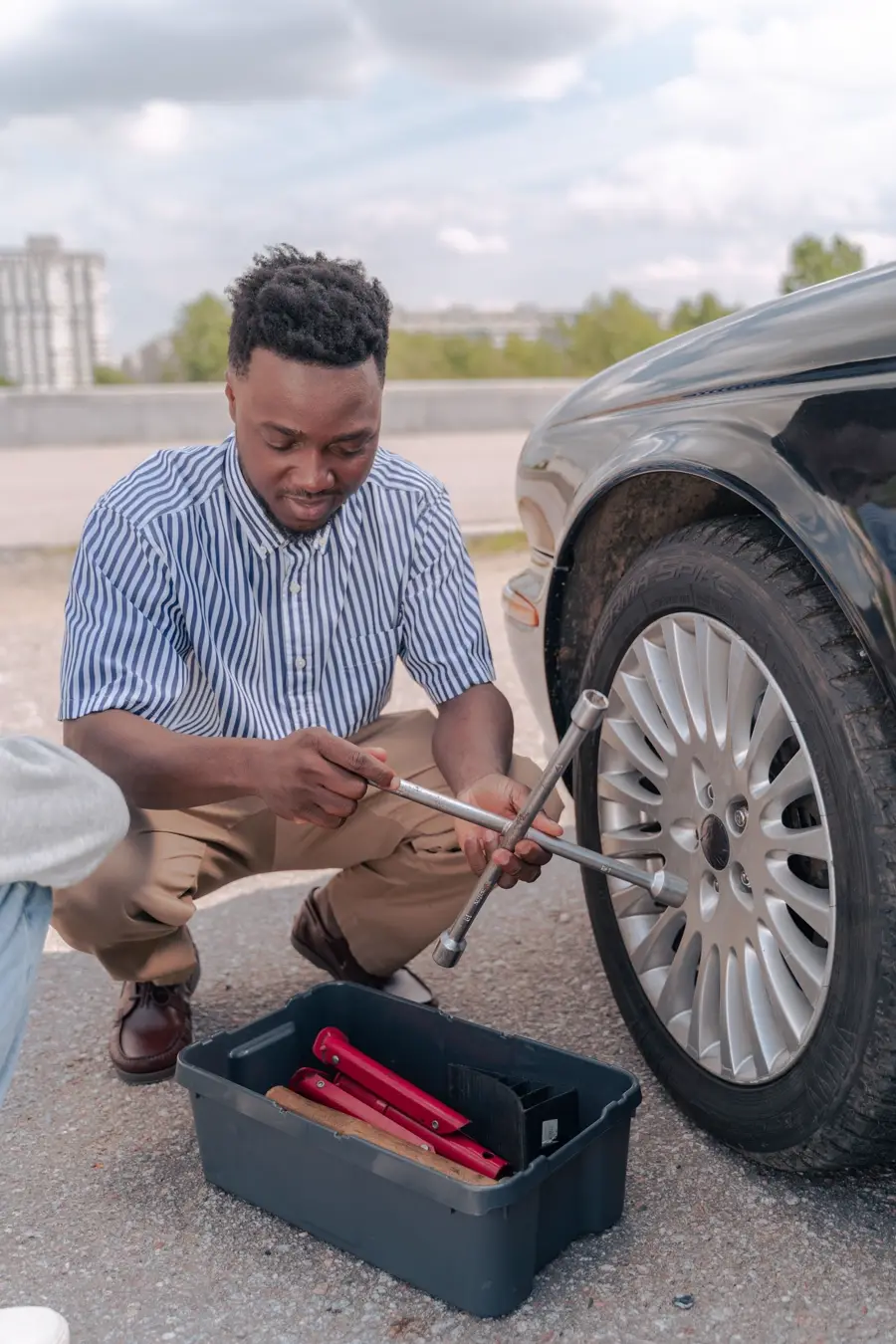 A man loosening lug nuts on a car wheel at the roadside (representative photo)